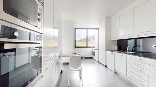 a white kitchen with white appliances and white cabinets at Azores Pico Salomão T4 Apartment - Super Spacious in Ponta Delgada