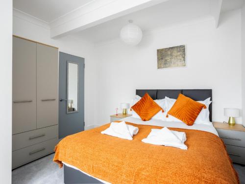 - une chambre avec un grand lit et une couverture orange dans l'établissement Large Modern Family Home Windsor, à Windsor