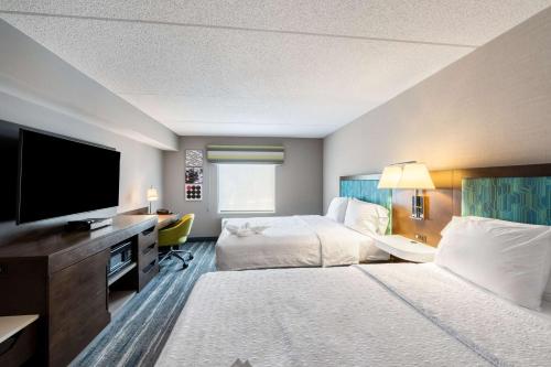 a hotel room with two beds and a flat screen tv at Hampton Inn & Suites Poughkeepsie in Spackenkill
