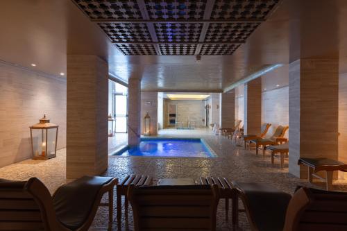 een zwembad in een gebouw met stoelen en een tafel bij Hotel Oasi Di Kufra in Sabaudia