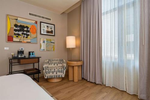 a bedroom with a bed and a chair and a window at Hilton San Diego Gaslamp Quarter in San Diego