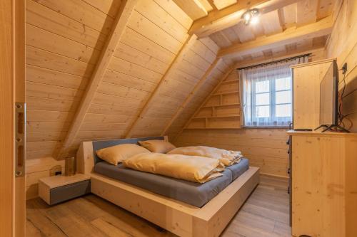 łóżko w drewnianym domku z oknem w obiekcie Wellness Chalet Kohútka w mieście Lazy pod Makytou