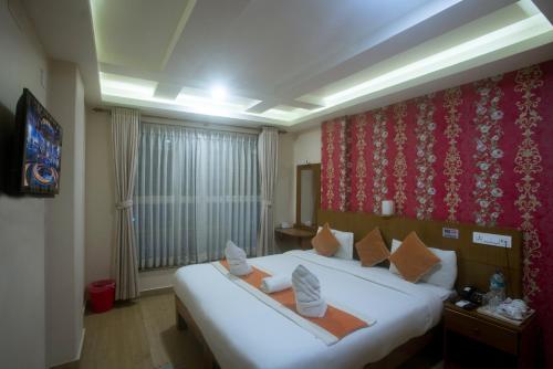 a bedroom with a large white bed with a red wall at Hotel Lake Himalaya in Pokhara