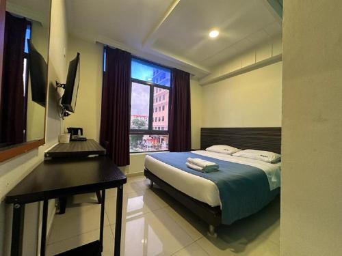 Schlafzimmer mit einem Bett, einem Schreibtisch und einem Fenster in der Unterkunft Darlene Hotel in Singapur
