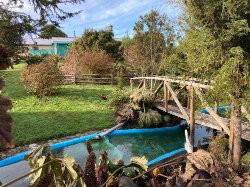 a wooden bridge over a pond in a garden at El Viloche - Casa de campo con tinaja in Puerto Montt