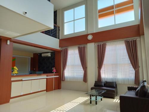 a living room with a couch and two windows at Karunia Hotel in Purwodadi