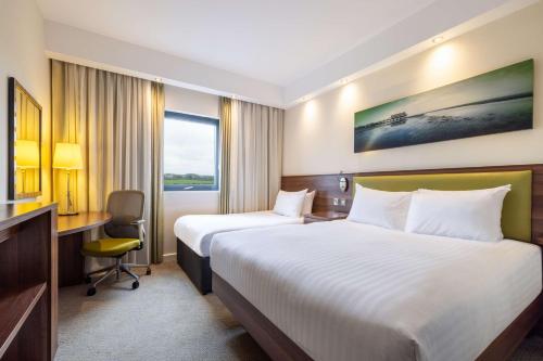 a hotel room with two beds and a desk at Hampton By Hilton Humberside Airport in Kirmington
