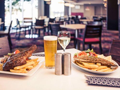 uma mesa com dois pratos de comida e um copo de cerveja em Mercure Orange em Orange