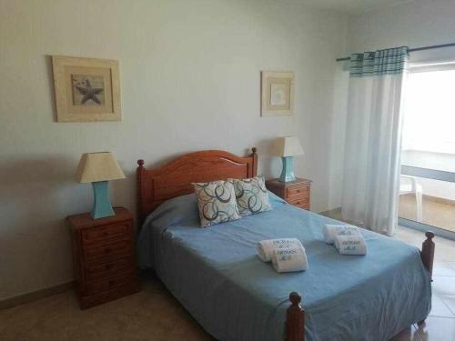 a bedroom with a blue bed with two night stands and a window at Ocean Quarteira Vista Mar e central in Quarteira