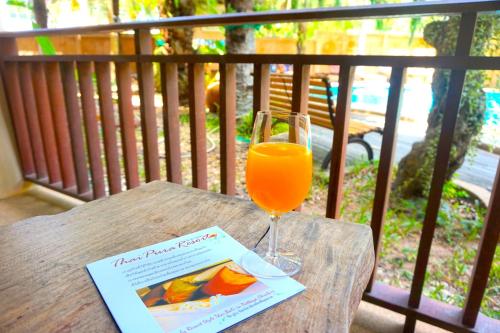 a glass of orange juice sitting on a wooden table at Thai Pura Resort in North Pattaya
