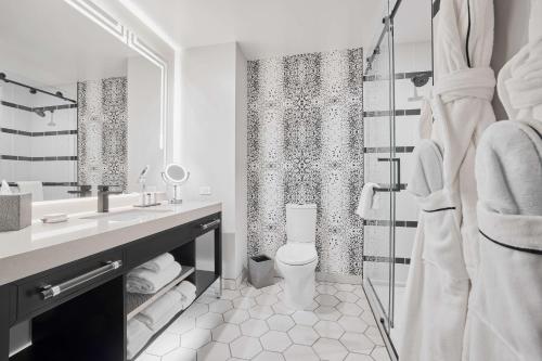 a white bathroom with a toilet and a shower at The Godfrey Detroit, Curio Collection By Hilton in Detroit