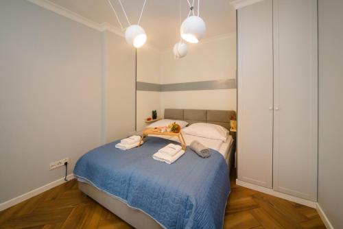 um pequeno quarto com uma cama azul e 2 toalhas em Maya's Flats & Resorts 34 - Chmielna 73 em Gdansk