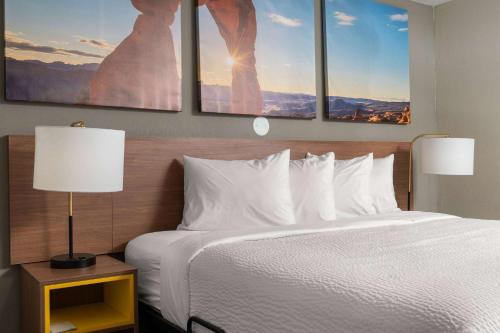 a bedroom with a bed with three paintings on the wall at Days-Inn by Wyndham Albuquerque I-25 in Albuquerque