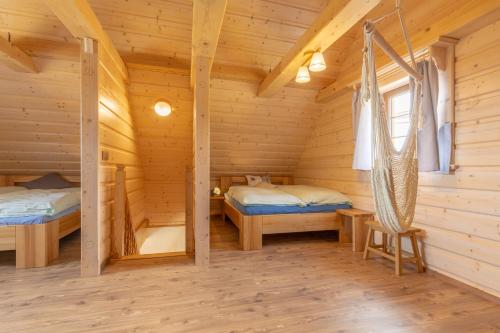 Dormitorio en cabaña de madera con 2 camas y hamaca en Malebný chalet Benešky en Velké Karlovice