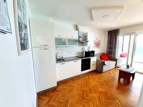 a kitchen with white cabinets and a wooden floor at Apartment Anton in Baška