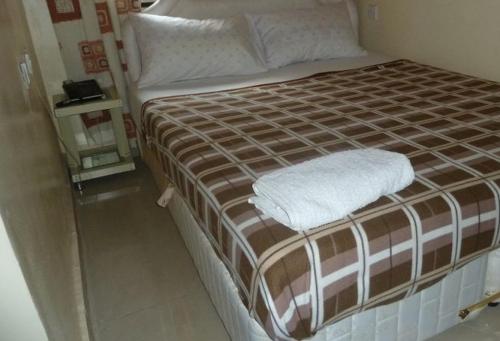 uma cama com lençóis e almofadas castanhos e brancos em Room in Lodge - Vision Serviced Apartments em Asaba