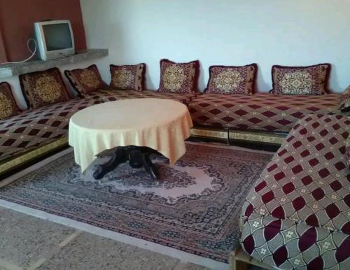 ein Wohnzimmer mit einem Sofa und einem Hund unter einem Tisch in der Unterkunft Beach house in Kenitra