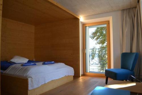 a bedroom with a bed and a chair and a window at Hotel des Alpes Dalpe in Dalpe