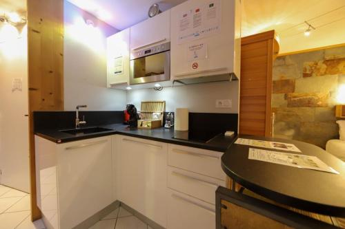 a kitchen with white cabinets and a black counter top at Le Cocon - Lofts & Lakes certified 4-stars in Annecy