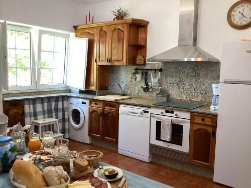 una cocina con armarios de madera y electrodomésticos blancos en Turismo Rural O Xastre de Anos, en Cabana de Bergantiños