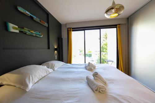 un grande letto bianco in una stanza con finestra di Le Superbe - T4 avec parking à 5 min du lac - 4 ad Annecy