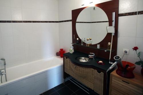 La salle de bains est pourvue d'un lavabo, d'un miroir et d'une baignoire. dans l'établissement Home on the roof w calm and tranquility, à Meythet