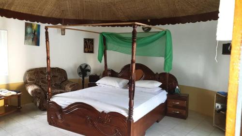 a bedroom with a canopy bed and a chair at Easy Time Lodge in Kololi