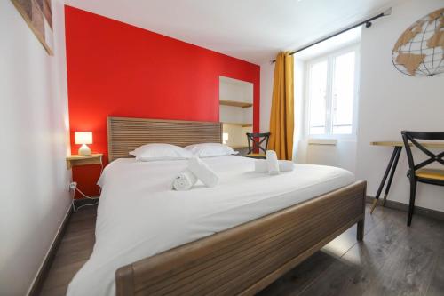 une chambre avec un grand lit avec un mur rouge dans l'établissement A l'aventure ! Joli T2 avec balcon centre ville, à Annecy