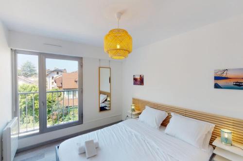 une chambre blanche avec un lit et une fenêtre dans l'établissement L'Avalanche - T2 avec parking, à Annecy