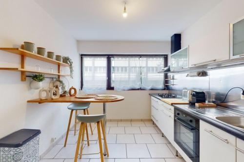 une cuisine avec des placards blancs et une petite table dans l'établissement Le Bucolique - appart 1 chambre, à Annecy