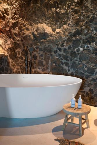 a white bath tub in a bathroom with a table at Dimora Cottanera in Castiglione di Sicilia