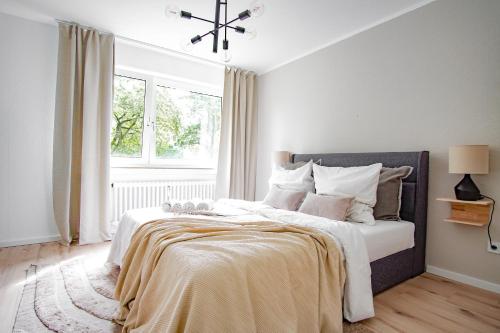 Schlafzimmer mit einem Bett mit weißer Bettwäsche und einem Fenster in der Unterkunft Homefy Wohlfühl-Apartment, mit Parkplatz, Balkon und Garten in Essen
