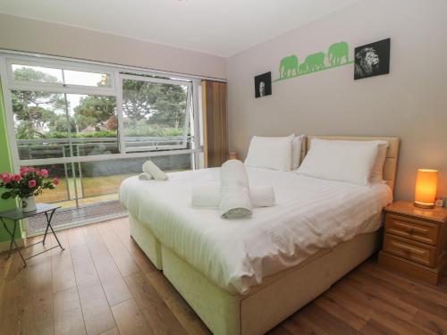 Un dormitorio con una gran cama blanca y una ventana en Flat 5 Fairwinds en Poole