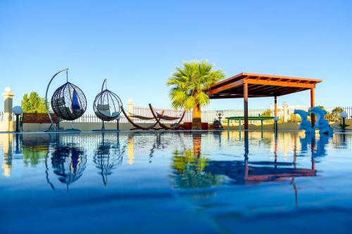 a pool of water with a pavilion and palm trees at Villa Rose in Kolimbia