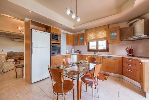 a kitchen with a table and a white refrigerator at Villa Rose in Kolimbia
