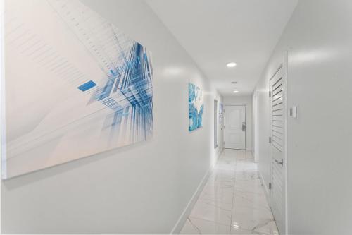a hallway with white walls and paintings on the walls at Ocean Club Treasure Island Hotel in St Pete Beach