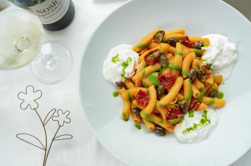 a white plate of pasta with vegetables and sour cream at Parc Hotel Du Lac in Levico Terme