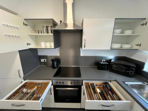 uma cozinha com armários brancos e um fogão em Premium Apartment 70qm 2 Zimmer Küche, Balkon, Smart TV, WiFi em Aalen