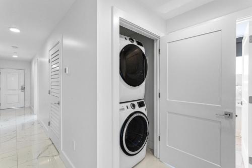 a white laundry room with a washer and dryer at Ocean Club Treasure Island Hotel in St Pete Beach