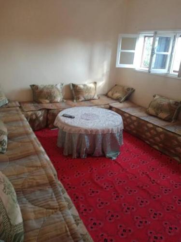 una camera con un divano e un tavolo su un tappeto rosso di appartement au centre ville a Beni Mellal