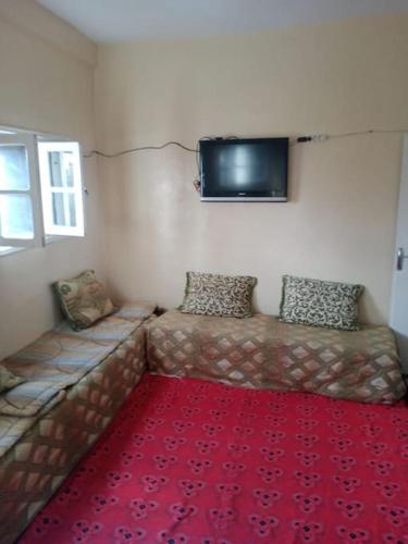 una camera con un divano e un tappeto rosso di appartement au centre ville a Beni Mellal