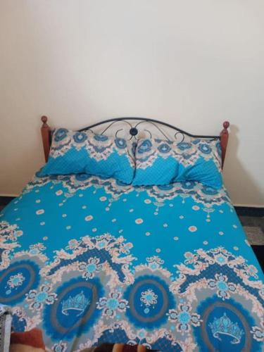 un letto con piumone e cuscini blu di appartement au centre ville a Beni Mellal
