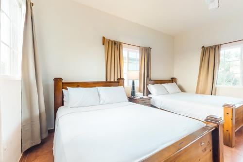two beds in a bedroom with two windows at Isebei Guest House Gold Standard Certified in Hopkins
