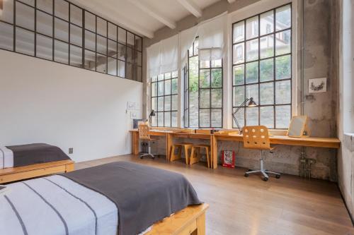 a bedroom with a bed and a desk and windows at Design Loft with Private Parking by Rent All Como in Como