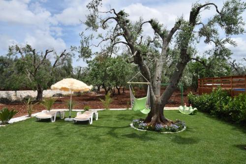 a garden with a tree and chairs and a swing at villa Antony in San Michele Salentino