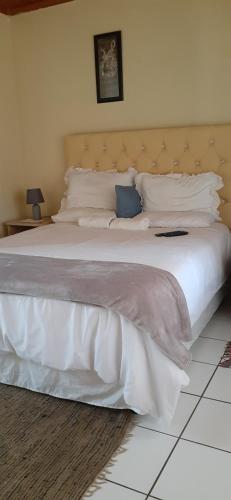 1 dormitorio con 1 cama grande con sábanas y almohadas blancas en Kwesethu Guesthouse, en Empangeni