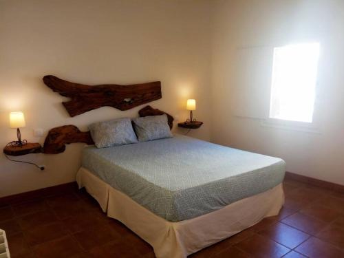 1 dormitorio con 1 cama con 2 lámparas en la pared en El Olivo, en Torre del Compte