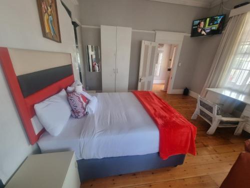 een slaapkamer met een groot bed en een rode deken bij AIDEN'S GUEST HOUSE in Port Elizabeth