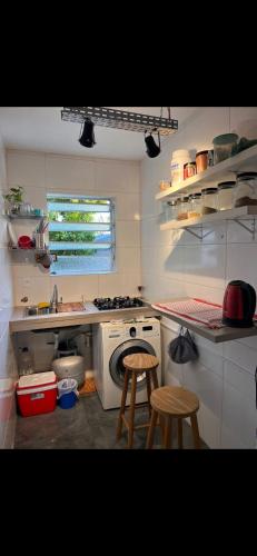 a kitchen with a stove and a sink and two stools at Studio Fabriketa in Novo Hamburgo