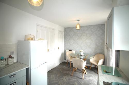 uma cozinha com uma mesa e um frigorífico branco em Ashington - 2 Bedroom House - Beautifully Decorated & Furnished - Large Garden em Ashington
